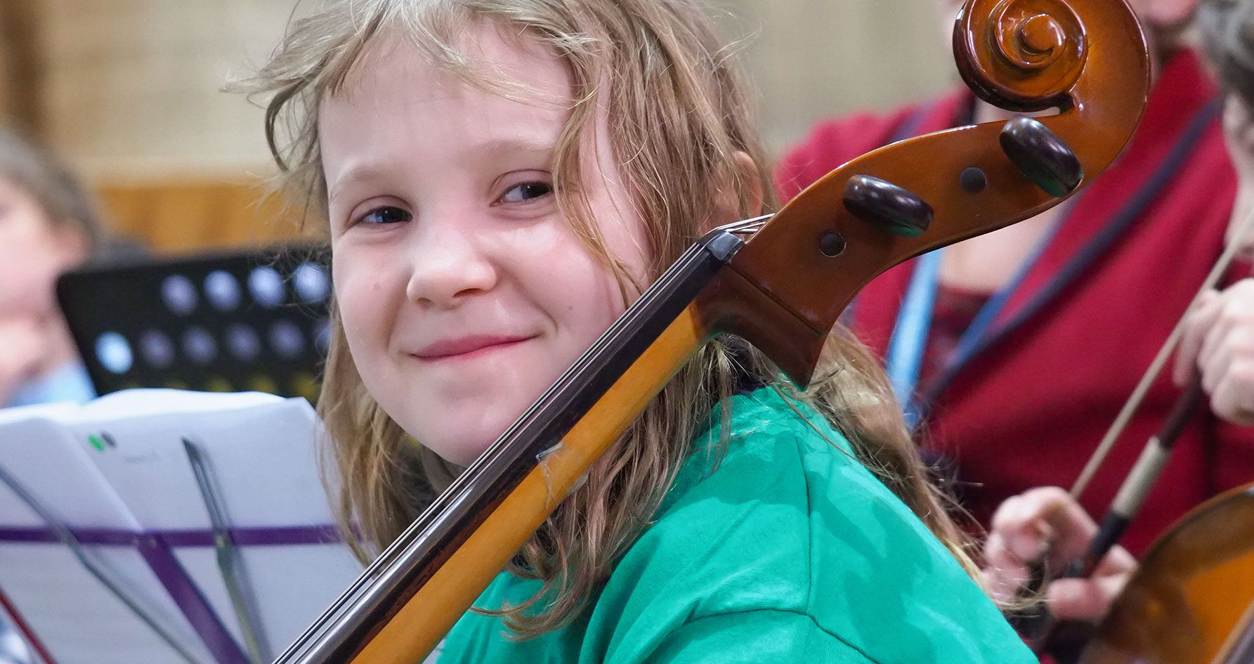 Girl smiling whilst holding string instrument