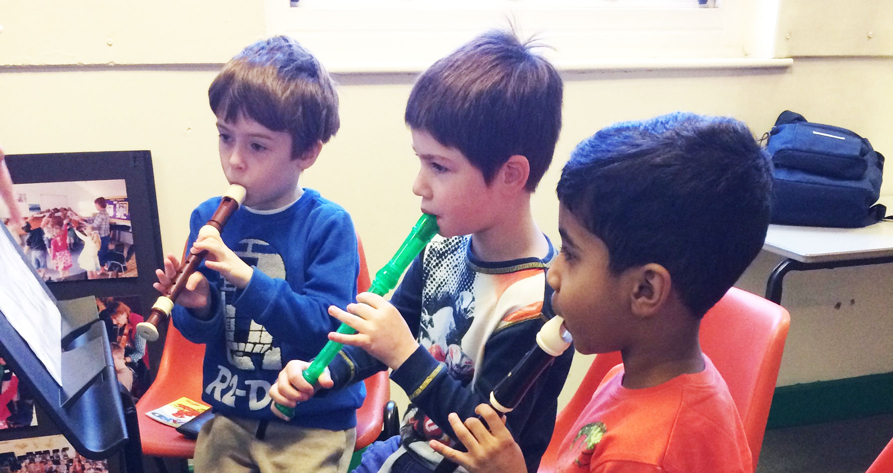 Three boys learning to play the recorder