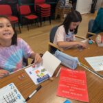 Child smiling with smarties and workbook