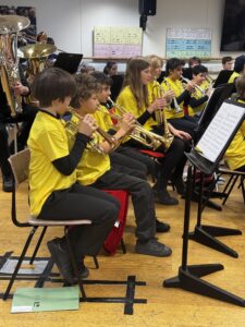 Group of students playing trumpets sat down