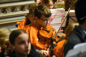 Boy wearing glasses playing violin